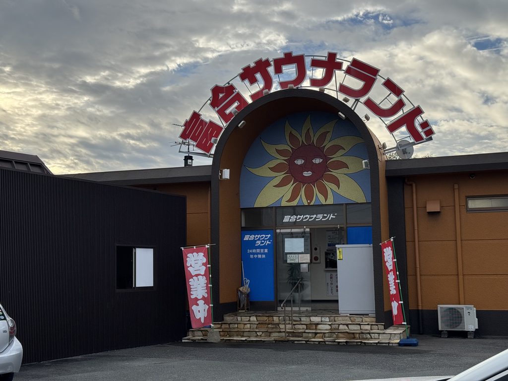 富合サウナランドの外観。赤い文字の看板と大きな太陽の絵