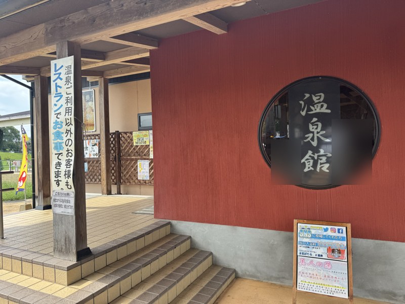 川の駅船小屋 恋ぼたる 温泉館の入口。赤い壁に丸窓の「温泉館」の文字